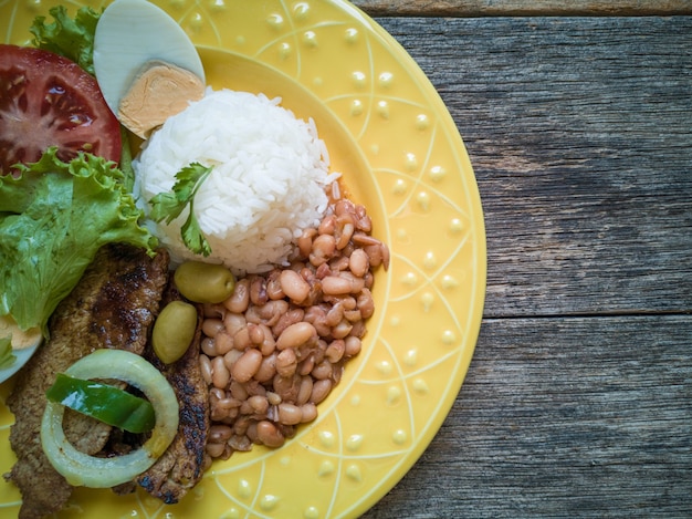 Plato de comida tradicional brasileña Frijoles arroz carne y ensalada vista superior.