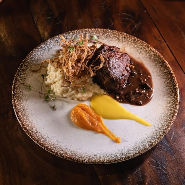 Un plato de comida con un trozo de carne con salsa.