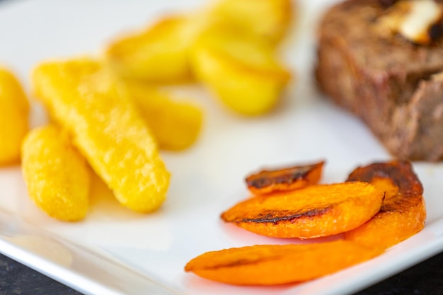 Un plato de comida con un trozo de carne y un trozo de pan al lado.