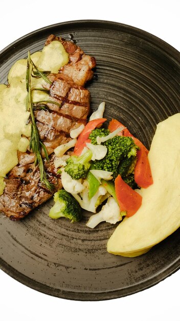 un plato de comida con una variedad de verduras, incluyendo bistec, brócoli y verduras