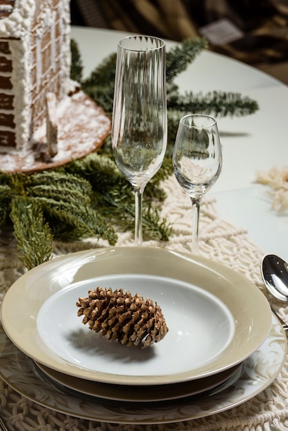 Un plato con un cono de abeto en una mesa festivamente puesta. Composición de Navidad festiva con enfoque selectivo.