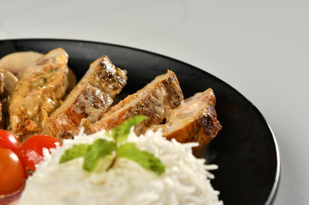 Un plato de costillas de cerdo con arroz y tomate