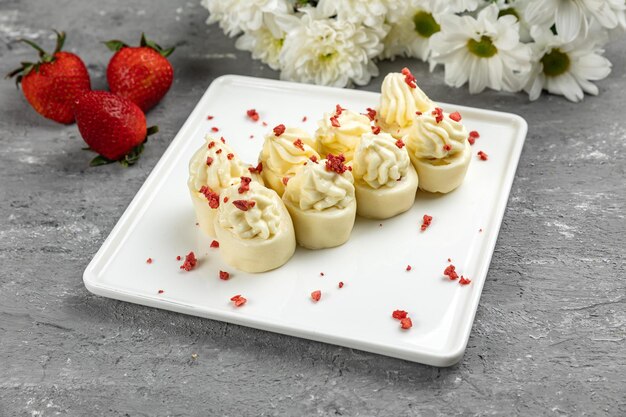 Un plato de cremas de queso crema con fresas al lado