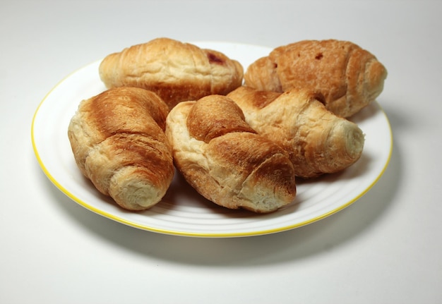 Un plato de croissants con borde amarillo y borde blanco.