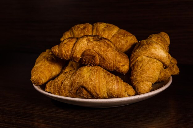 Plato con croissants recién hechos en una mesa de madera oscura.