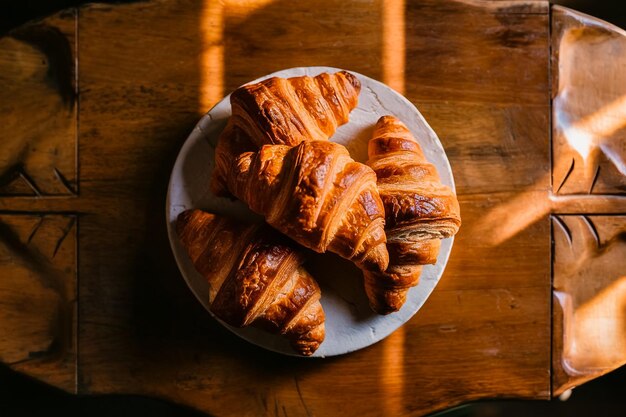 Foto un plato de croissants con el reflejo del sol en la mesa