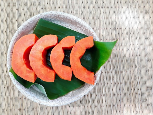 Un plato de cuatro piezas de papaya en la hoja de plátano, fresca, dulce y buena para la salud.