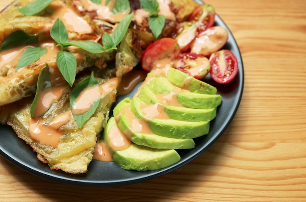 Plato de deliciosa ensalada de aguacate y tomate con rebanadas de Frittata