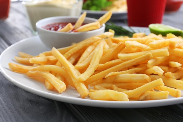 Plato con deliciosas papas fritas y salsa en primer plano de la mesa