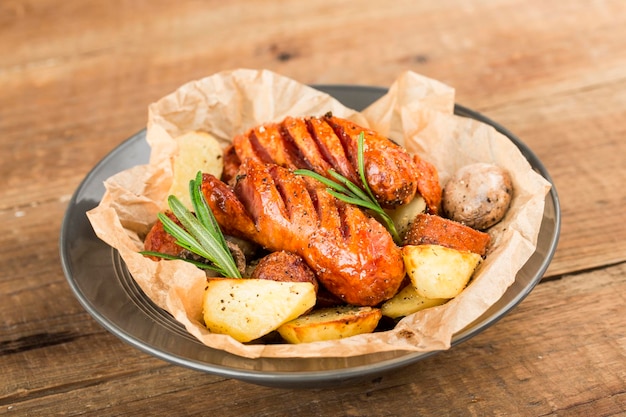 Foto un plato de deliciosas papas y salchichas al horno.