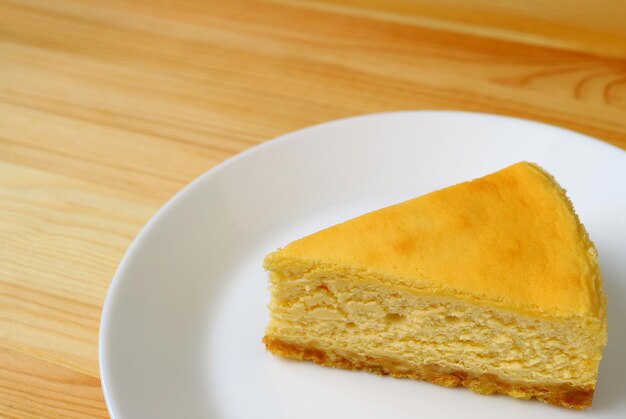 Plato de delicioso pastel de queso amarillo cremoso al horno servido en una mesa de madera