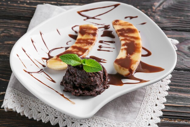 Plato con delicioso postre vertido con salsa de chocolate en la mesa