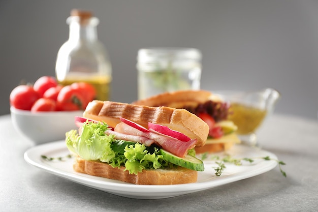 Plato con delicioso sándwich en mesa