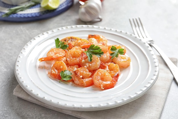 Plato con deliciosos camarones fritos y ajo picado en la mesa