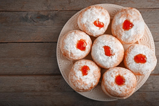 Plato con deliciosos donuts sobre fondo de madera Concepto de celebración de Hanukkah