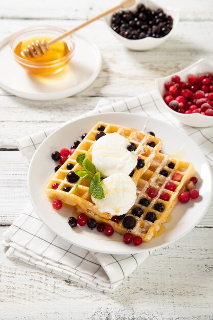 Plato con deliciosos gofres con fresas y helado.