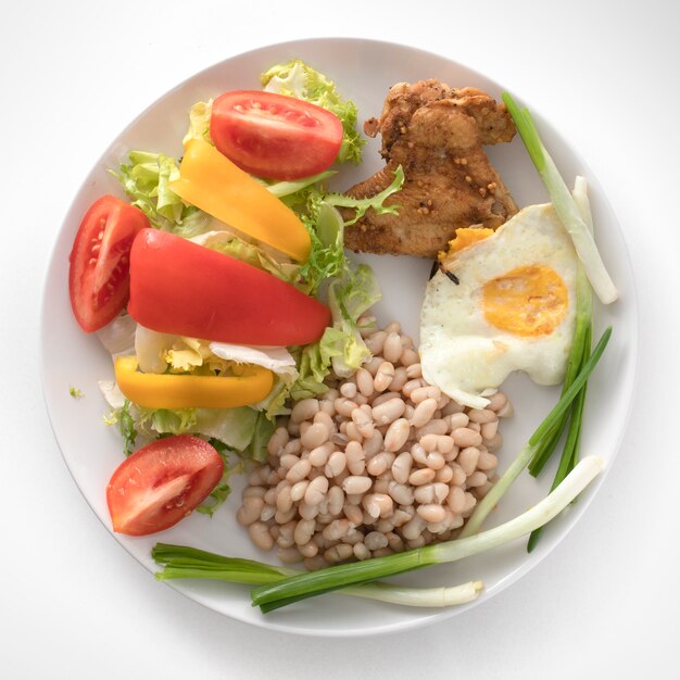 Un plato con un desayuno saludable. Frijoles, ala de pollo asado.