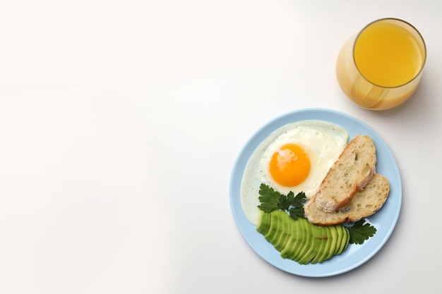 Plato de desayuno y vaso de jugo sobre fondo blanco.