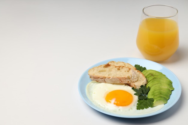 Plato de desayuno y vaso de jugo sobre fondo blanco.