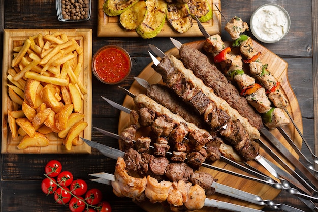 Plato elaborado a base de brochetas, pollo a la plancha, ternera, carne de cerdo con barbacoa y salsa Tzatziki servido con patatas fritas en la oscuridad.