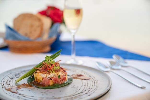 Plato de ensalada de atún en la mesa de comedor con champán para cenar en el restaurante.