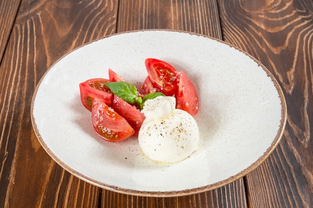 Plato de ensalada caprese con tomates resh y un trozo de mozzarella