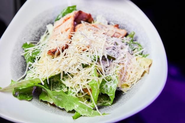 Un plato de ensalada César con pechuga de pollo y parmesano