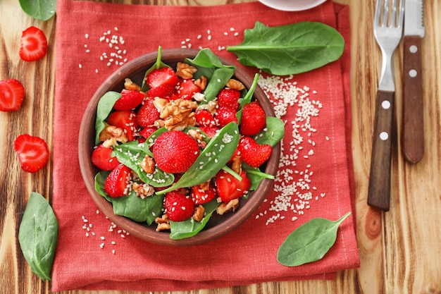 Plato de ensalada con espinacas, fresas y nueces en la mesa