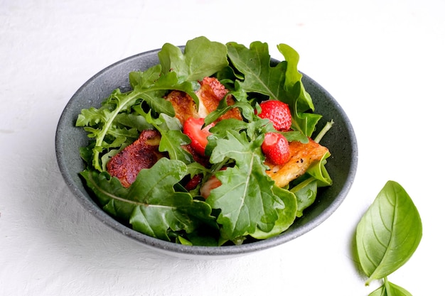 Plato con ensalada fresca de rúcula, plantas, queso, albahaca y fresa. Vista superior de la comida.