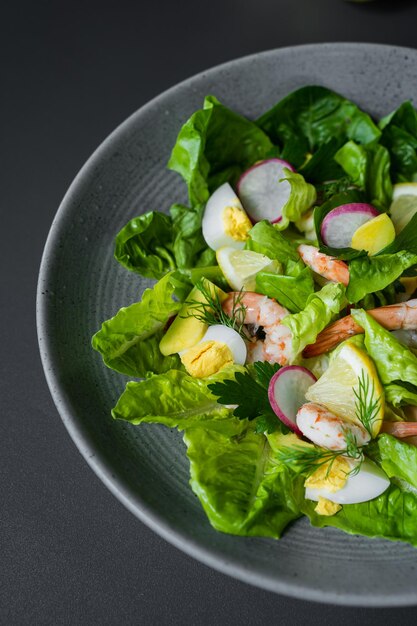 Un plato de ensalada de gambas con rodajas de limón y verduras.