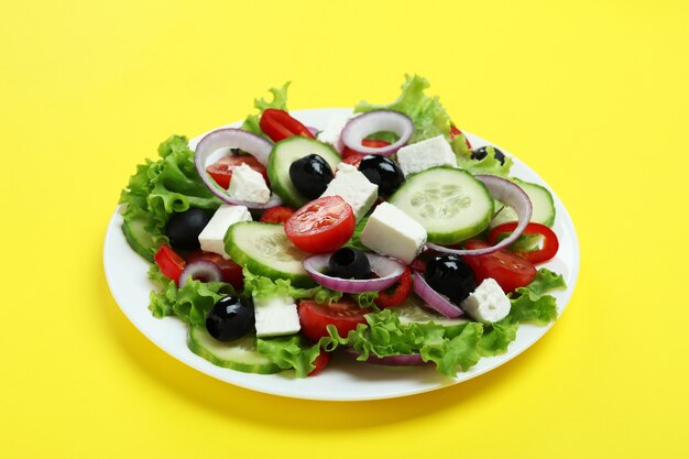 Plato de ensalada griega sobre fondo amarillo