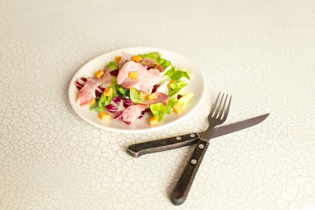 Plato de ensalada de hojas verdes, jamón y queso