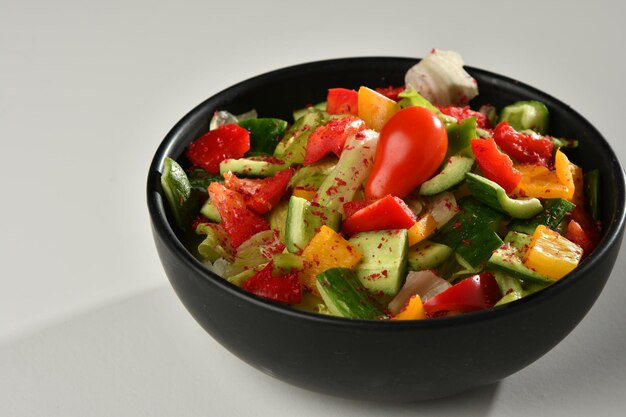 Un plato de ensalada de pepino con pimiento rojo al lado