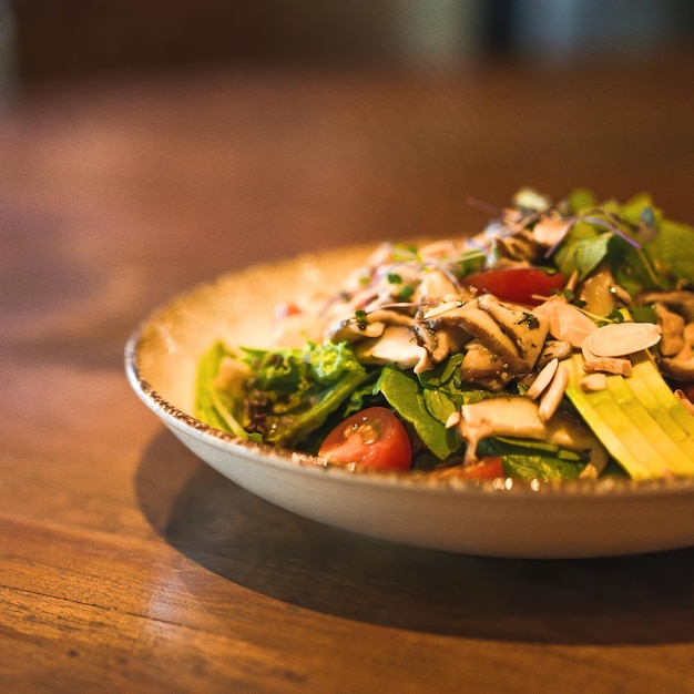 Un plato de ensalada con pollo, aguacate y tomates.