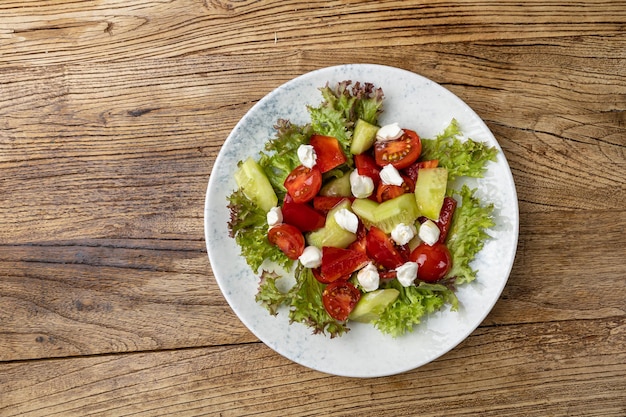 Un plato de ensalada con queso feta y pepino sobre una mesa de madera