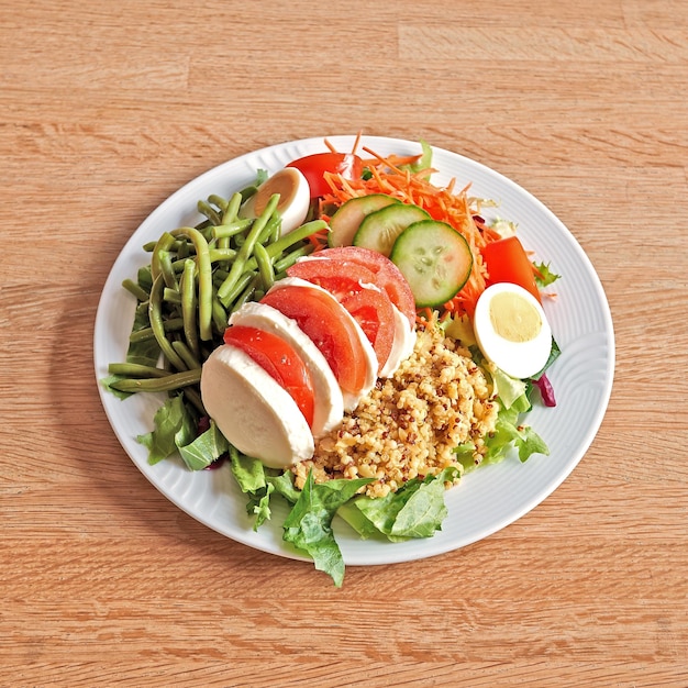 Plato con ensalada de tomate Mozzarella sobre mesa de madera