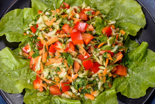 Plato de ensalada con verduras y verduras en una mesa de hormigón oscuro