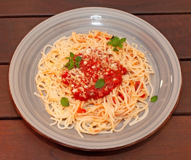 Un plato de espaguetis con salsa roja y perejil encima.