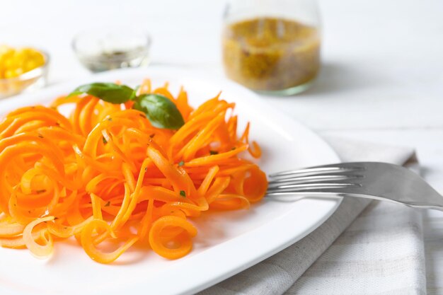 Plato con espaguetis de zanahoria cruda en primer plano de la mesa