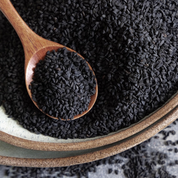 Plato de especias indias Comino negro nigella sativa o semillas de kalonji de cerca con una cuchara de madera