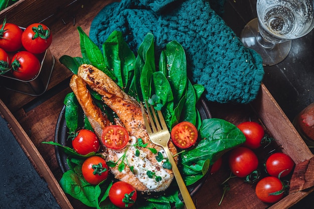 Un plato con espinacas crudas verdes frescas y tomates de salmón salvaje fritos y salsa de queso crema