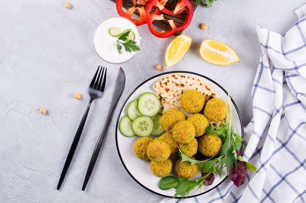 Plato de falafel al horno con pan de pita, salsa y hojas de ensalada