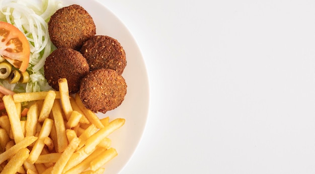 Plato de falafel con patatas fritas y ensalada sobre fondo blanco con espacio para texto