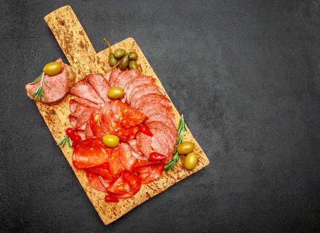 Plato de fiambre con salchichón y chorizo sobre tabla de madera de corcho