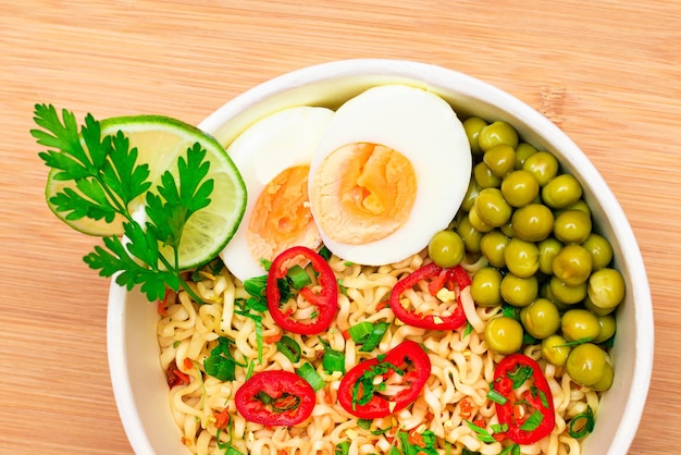 Plato de fideos con guisantes verdes, huevos, pimiento rojo y verduras