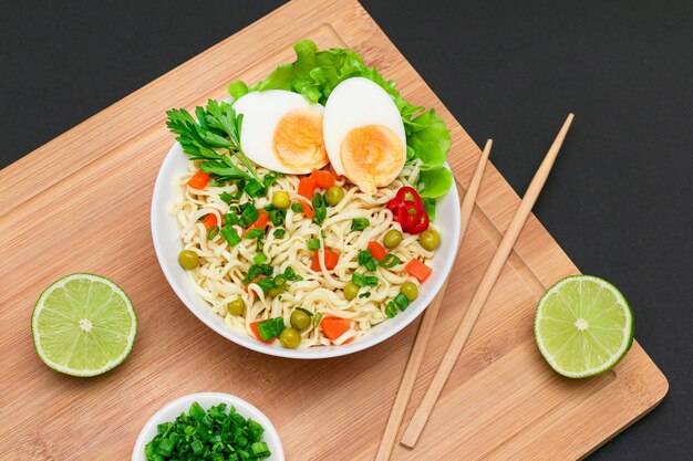 Plato de fideos con guisantes, zanahoria, huevos, pimiento rojo y verduras