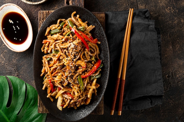 Foto plato de fideos soba de trigo sarraceno asiático con verduras, champiñones y pollo sobre fondo oscuro