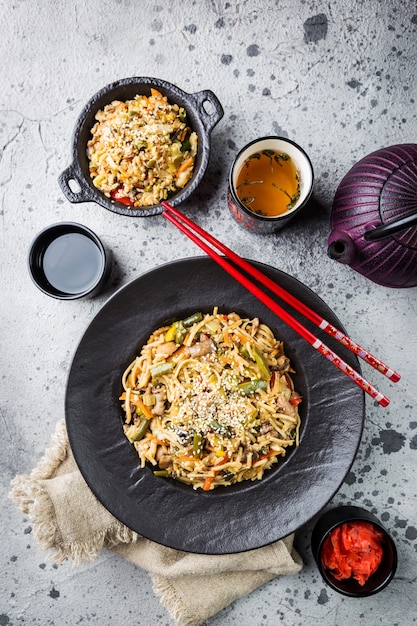 Plato de fideos wok o salteados con carne y verduras sobre piedra gris