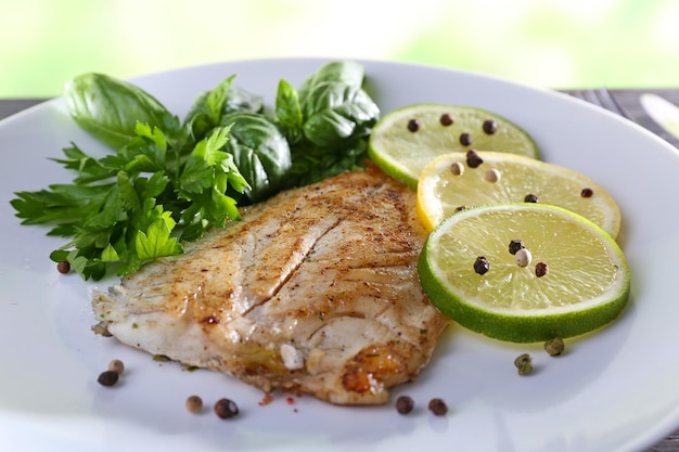 Plato de filete de pescado con verduras y limón en la mesa de cerca