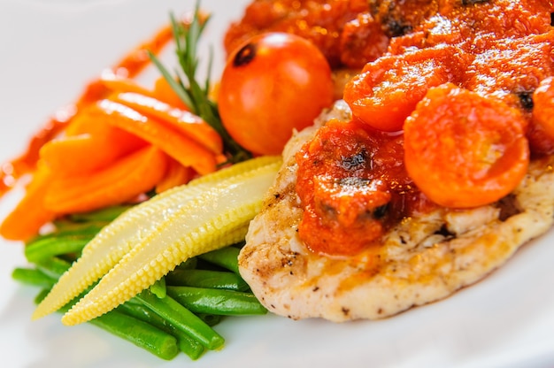 Plato de filete de pollo asado con verduras al vapor y salsa roja